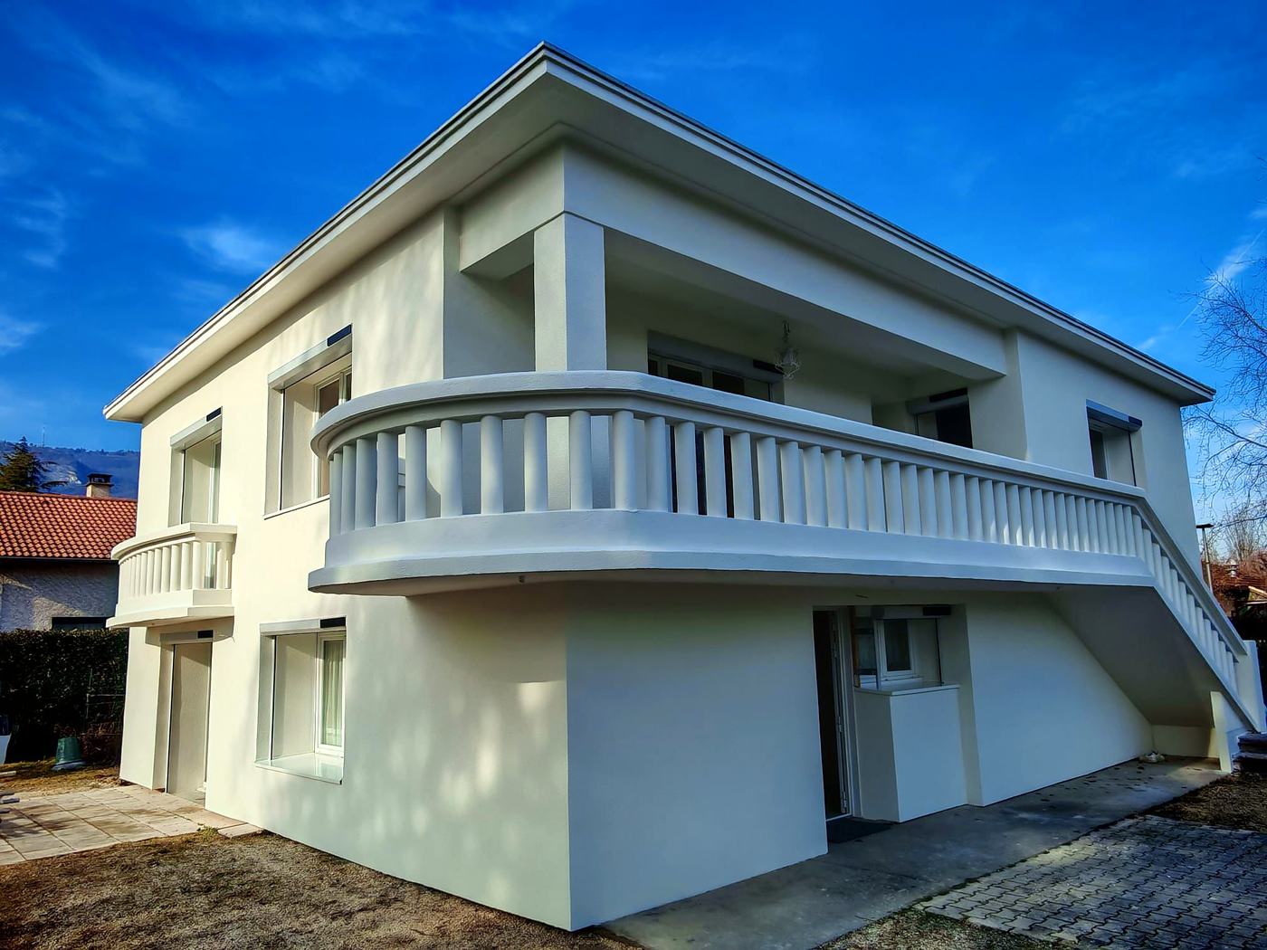 Façade refaite et isolée par l'extérieur par Rev'Iso, maison blanche à balcon arrondi
