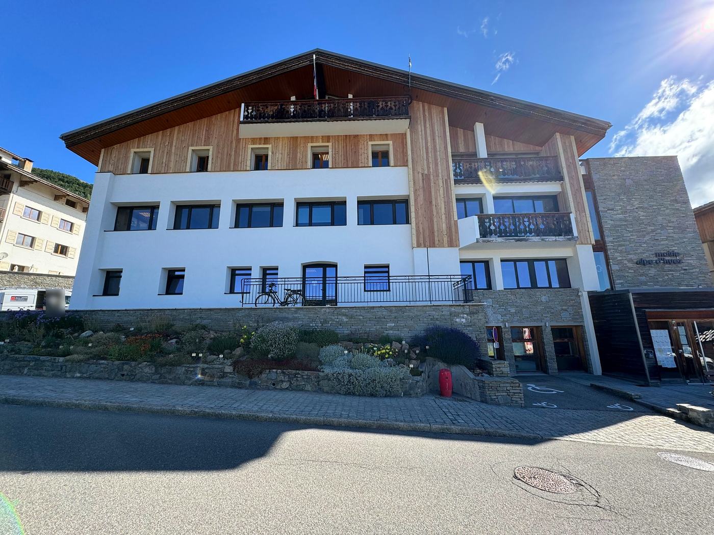 Mairie de L'Alpe d'Huez après isolation extérieure par Rev'Iso : façade blanche et bardage bois clair