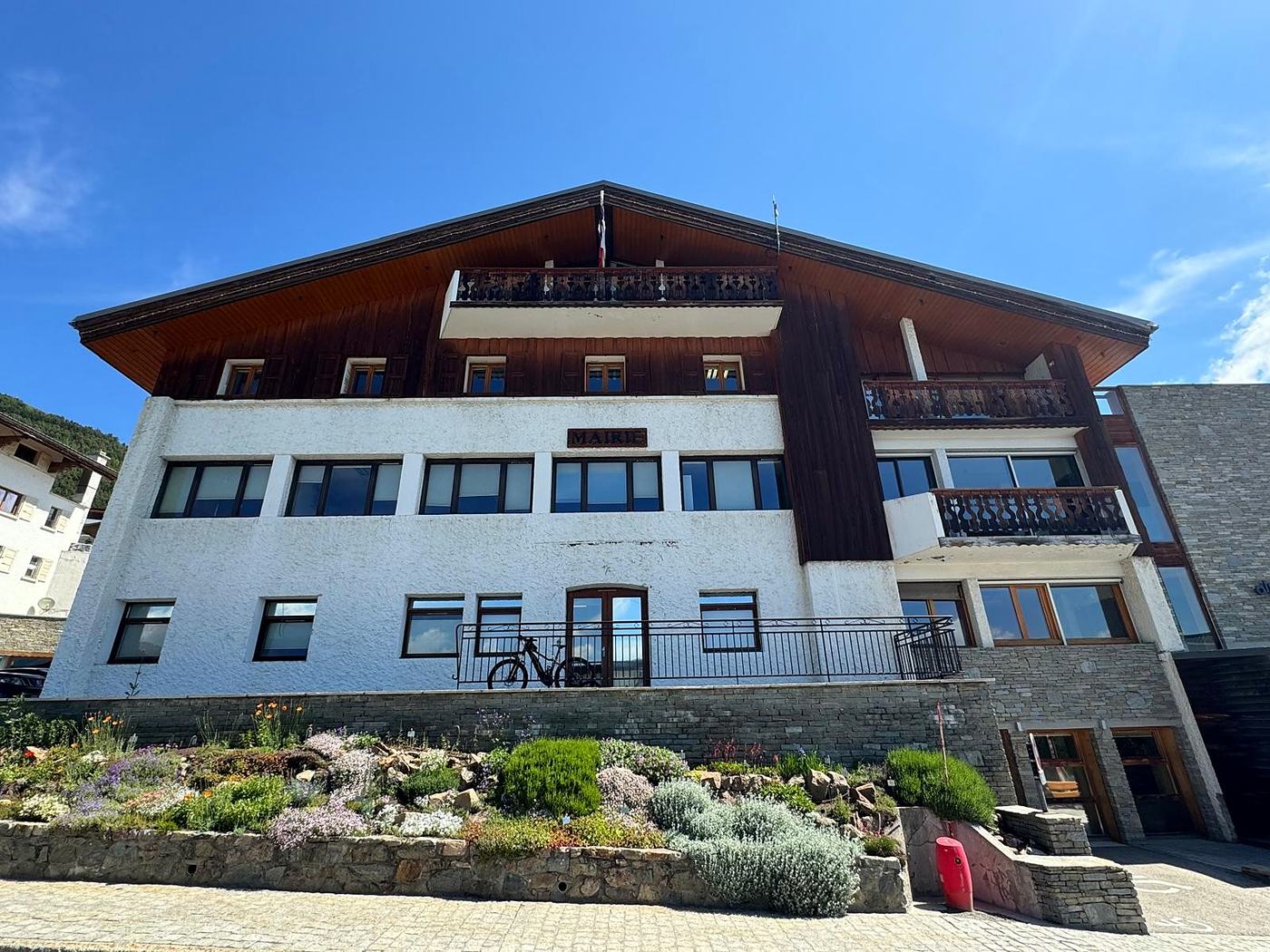 Façade principale de la mairie de L'Alpe d'Huez avant travaux : crépi ancien et bardage bois sombre